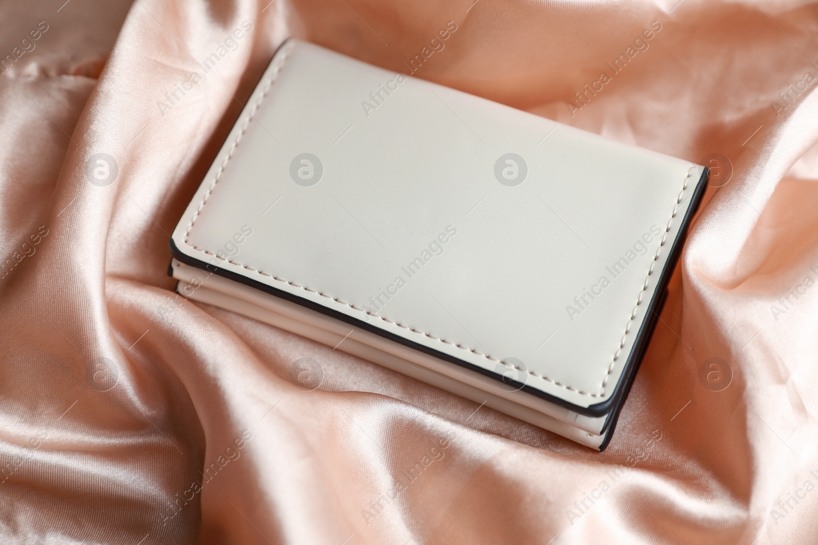 Photo of Stylish presentation of leather purse on silk fabric, closeup