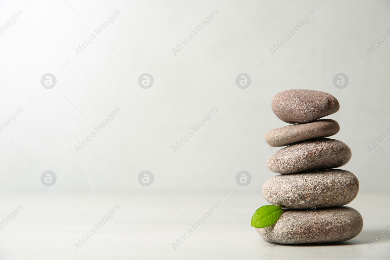 Photo of Stack of spa stones with leaf on light background. Space for text