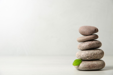 Photo of Stack of spa stones with leaf on light background. Space for text