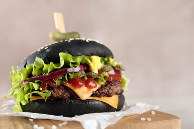 Photo of Board with black burger on table, closeup. Space for text