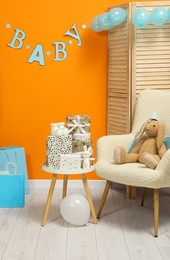 Photo of Baby shower party. Festive decor, booties, toys and gift boxes in stylish room