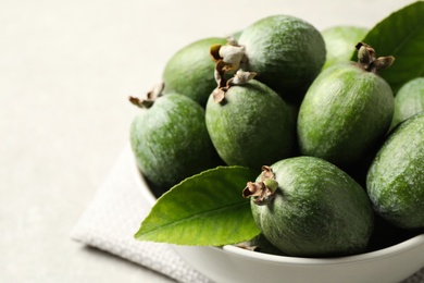 Photo of Delicious fresh feijoas in bowl on light grey table, closeup