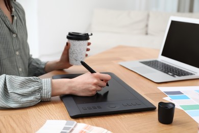 Professional designer with graphic tablet at wooden table, closeup