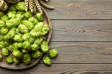 Photo of Tray with fresh green hops and wheat ears on wooden table, flat lay. Space for text