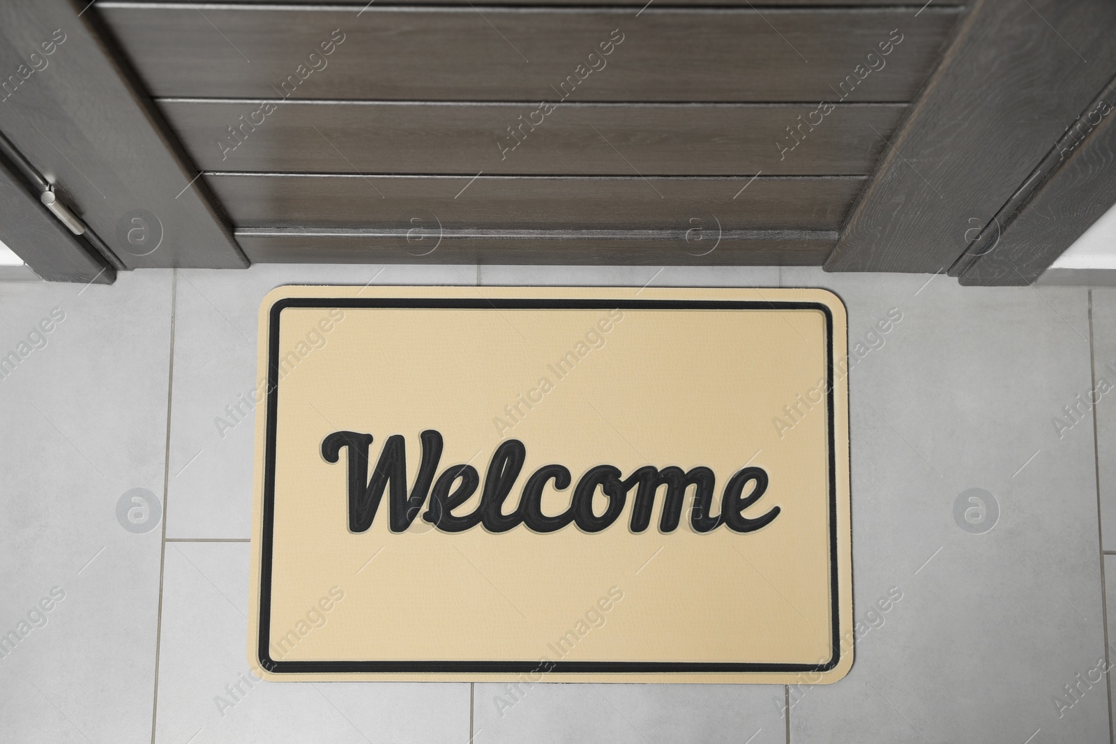 Photo of Beautiful beige doormat with word Welcome on floor near entrance, top view