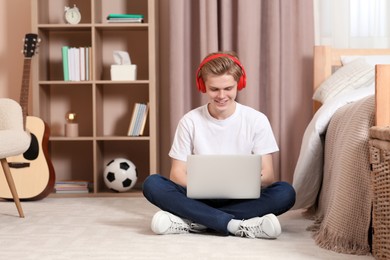 Photo of Online learning. Smiling teenage boy in headphones with laptop at home