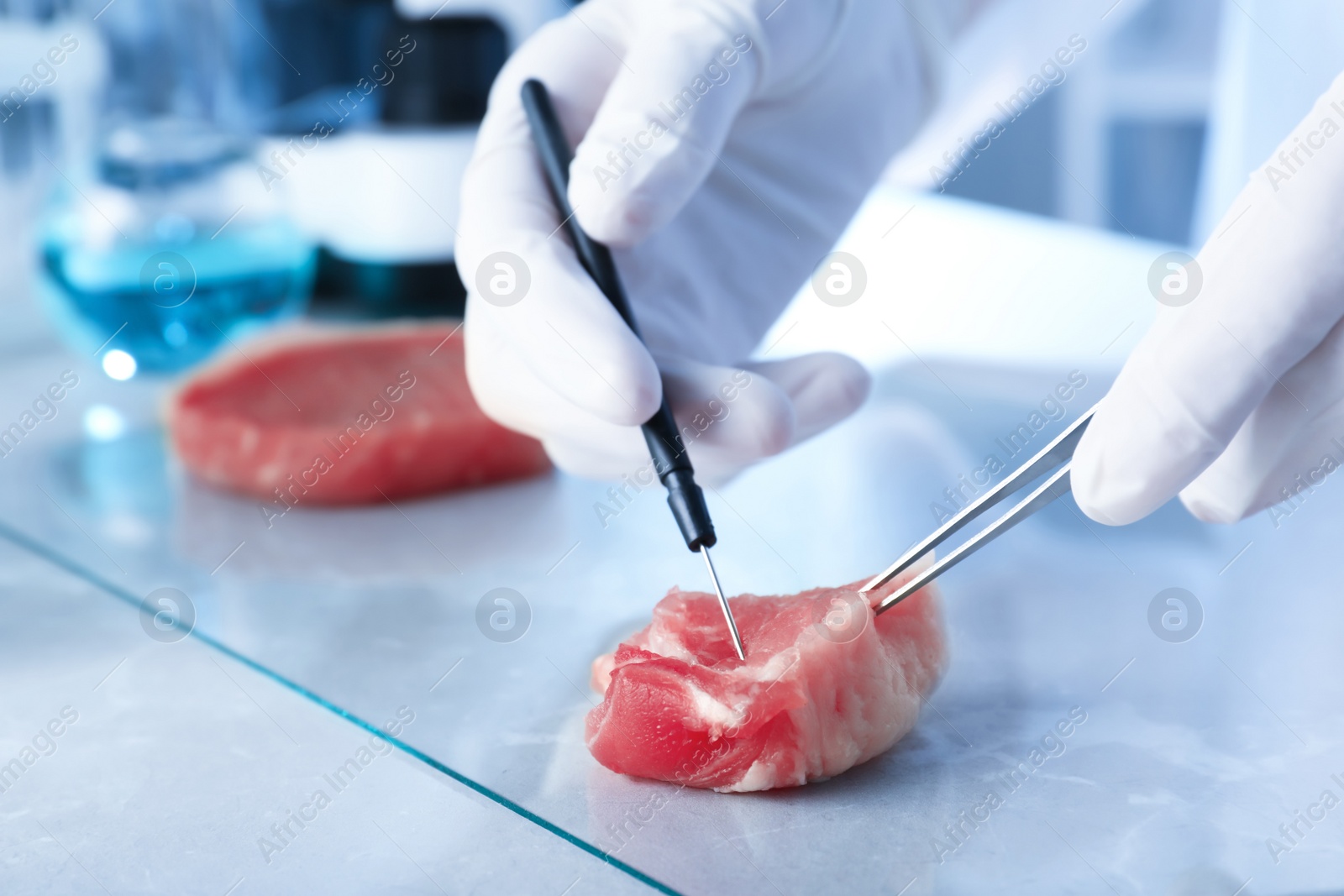 Photo of Scientist inspecting meat sample in laboratory, closeup. Food quality control