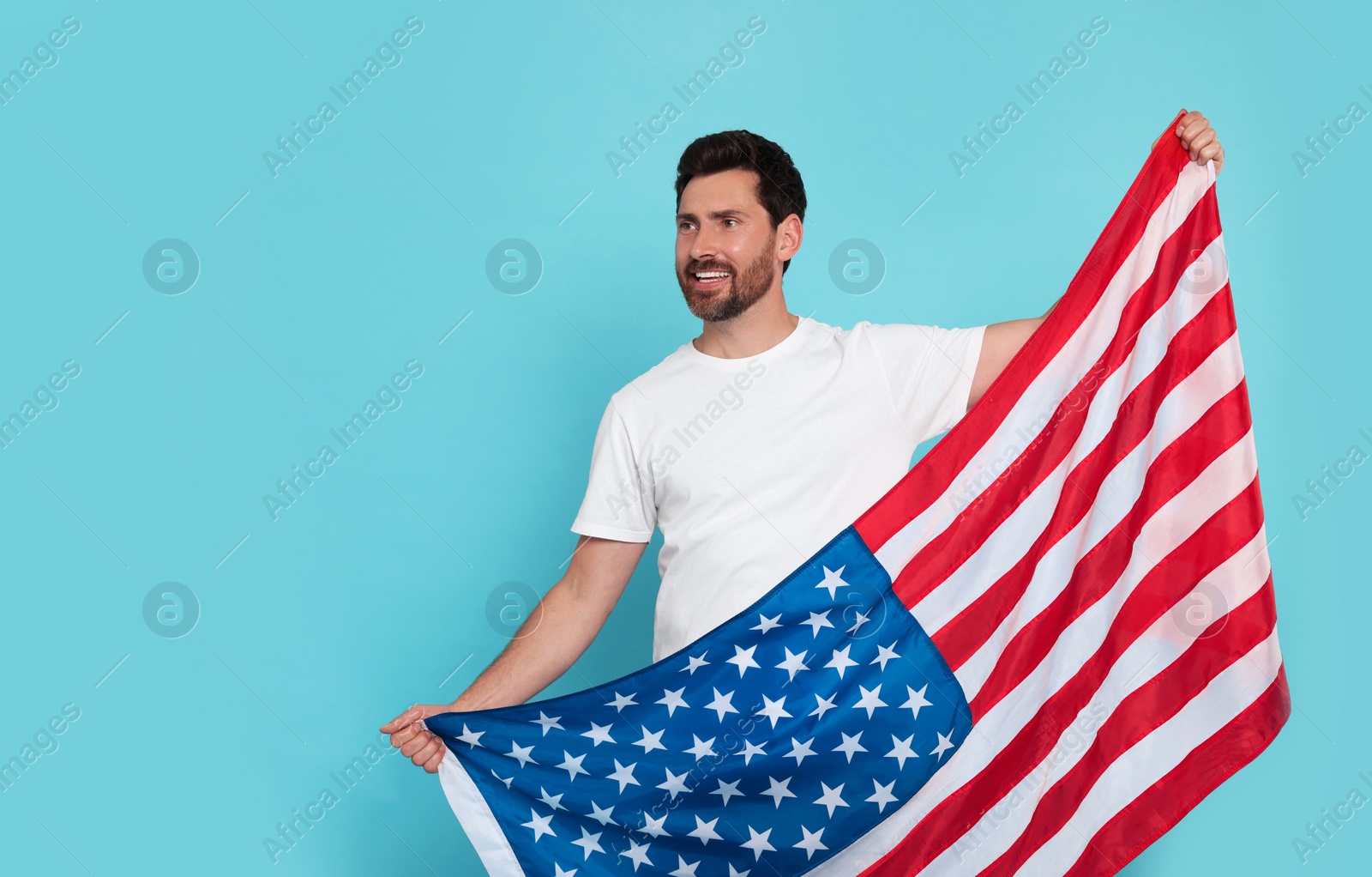 Photo of 4th of July - Independence Day of USA. Happy man with American flag on light blue background, space for text