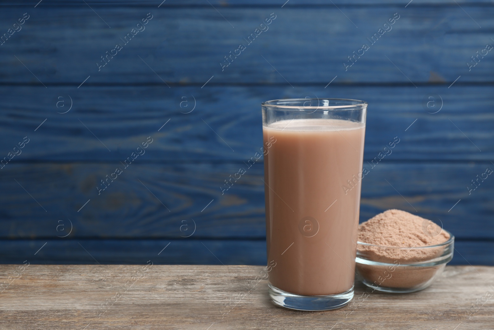 Photo of Protein shake and powder on wooden table, space for text