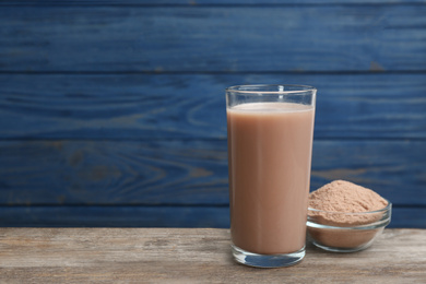 Protein shake and powder on wooden table, space for text