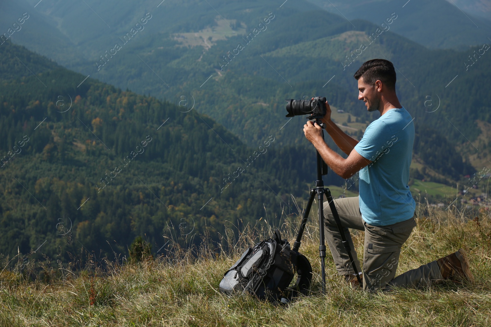 Photo of Man taking photo of mountain landscape with modern camera on tripod outdoors