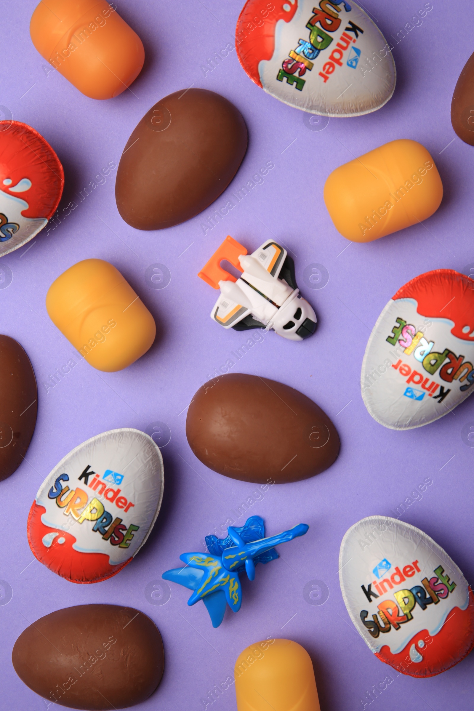 Photo of Sveti Vlas, Bulgaria - June 30, 2023: Kinder Surprise Eggs, toys and plastic capsules on violet background, flat lay