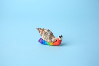 Photo of Snail made from plasticine on light blue background. Children's handmade ideas