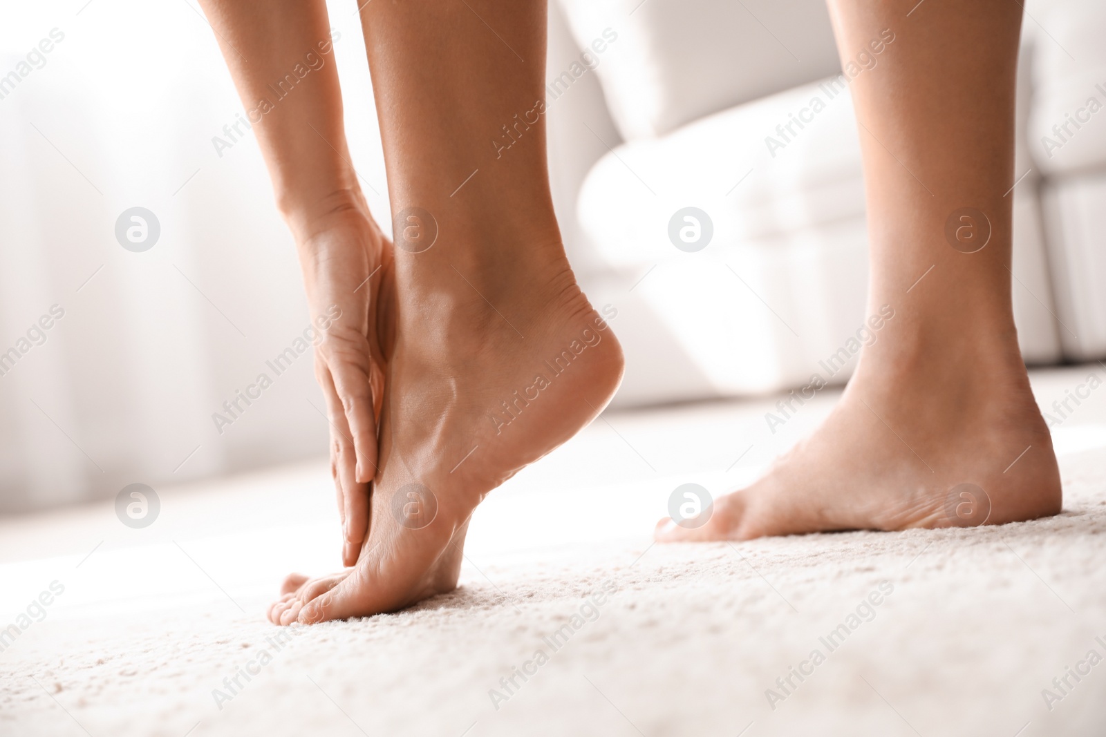 Photo of Young woman suffering from pain in foot indoors, closeup