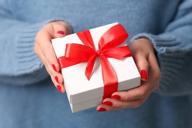 Photo of Christmas present. Woman holding gift box, closeup