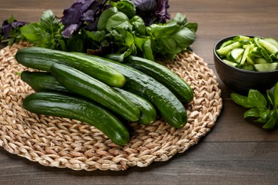 Photo of Fresh ripe cucumbers and basil on wooden table