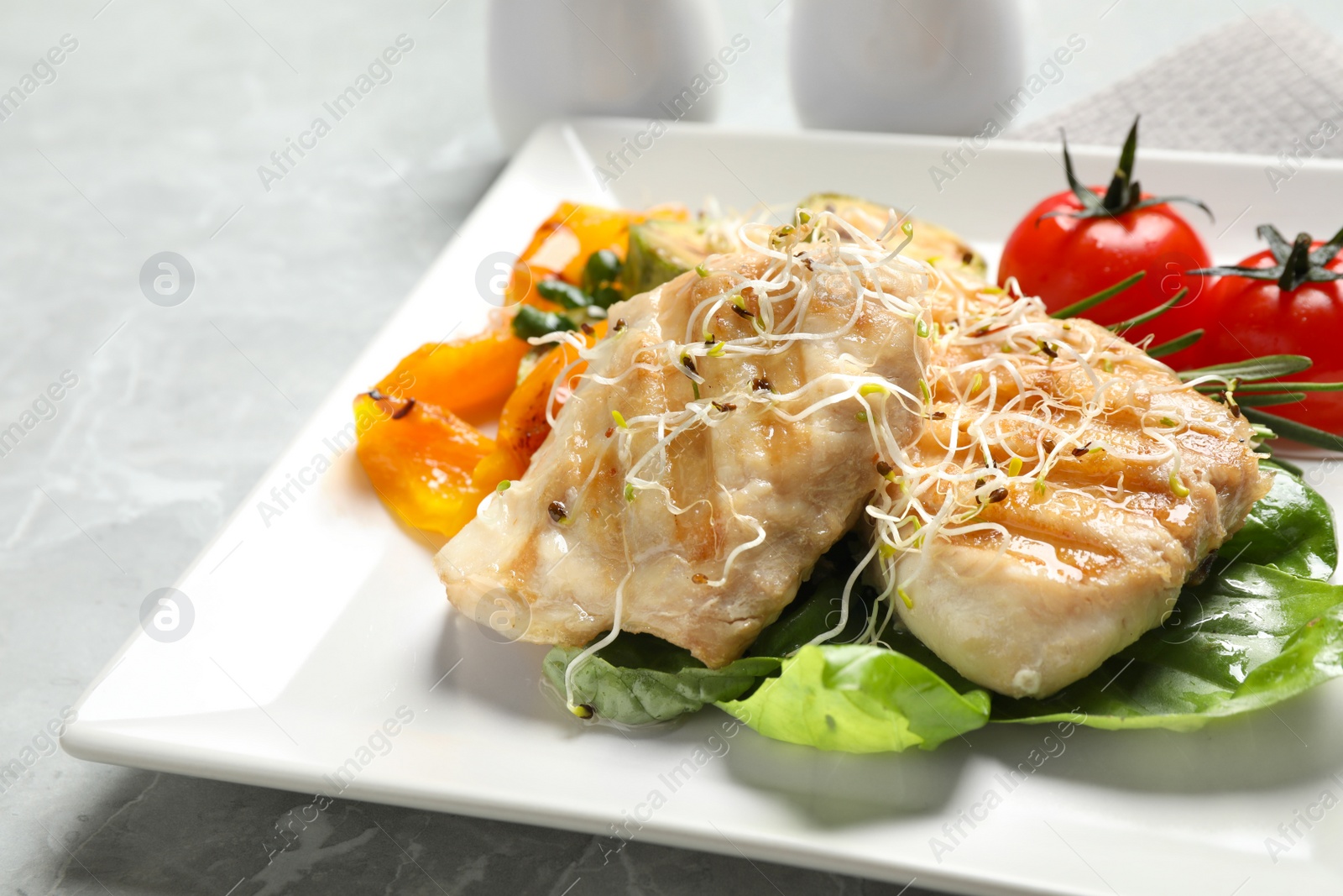 Photo of Tasty grilled fish on light grey marble table, closeup