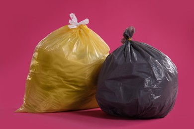 Trash bags full of garbage on pink background