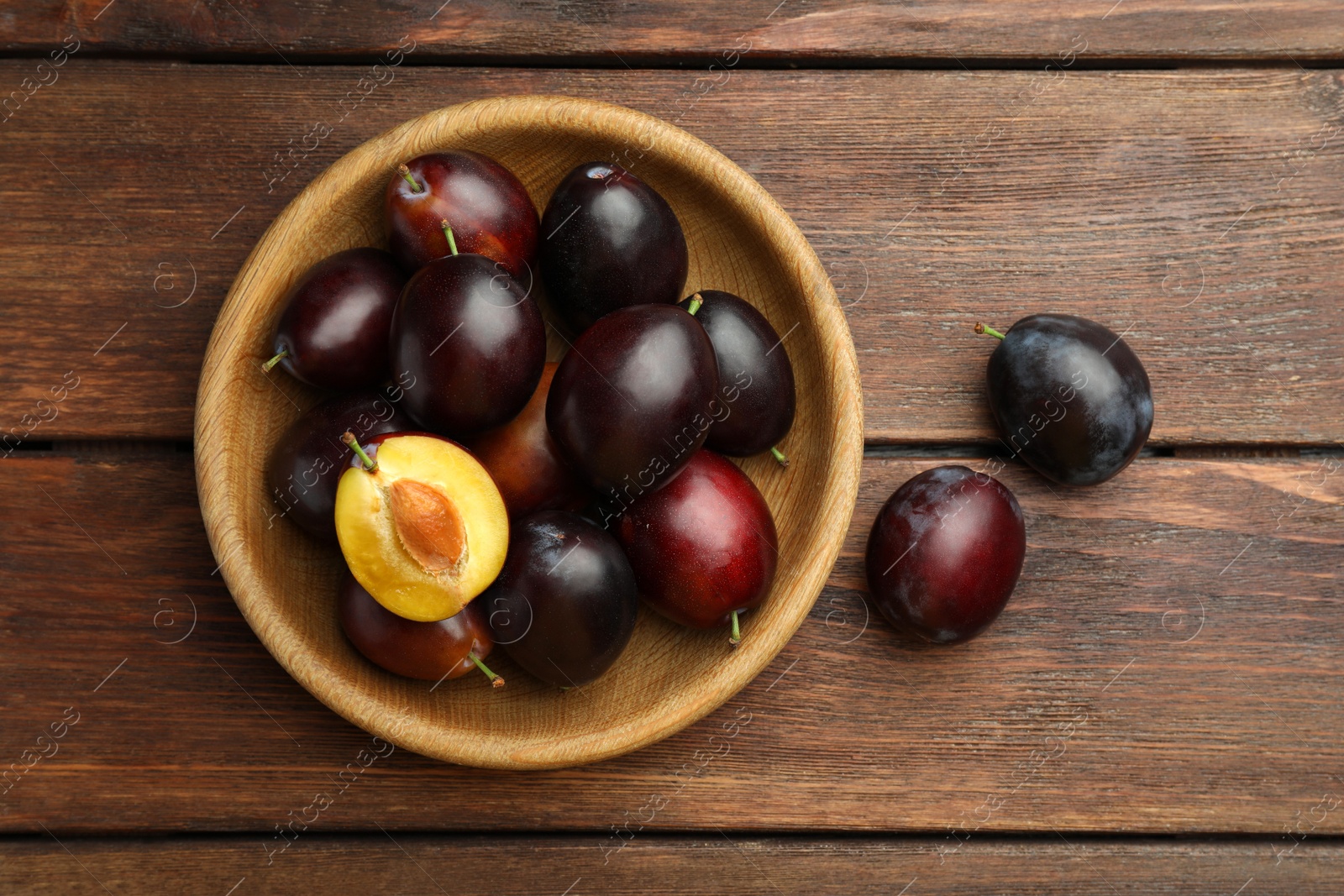 Photo of Tasty ripe plums on wooden table, flat lay