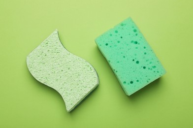 Color sponges on green background, flat lay