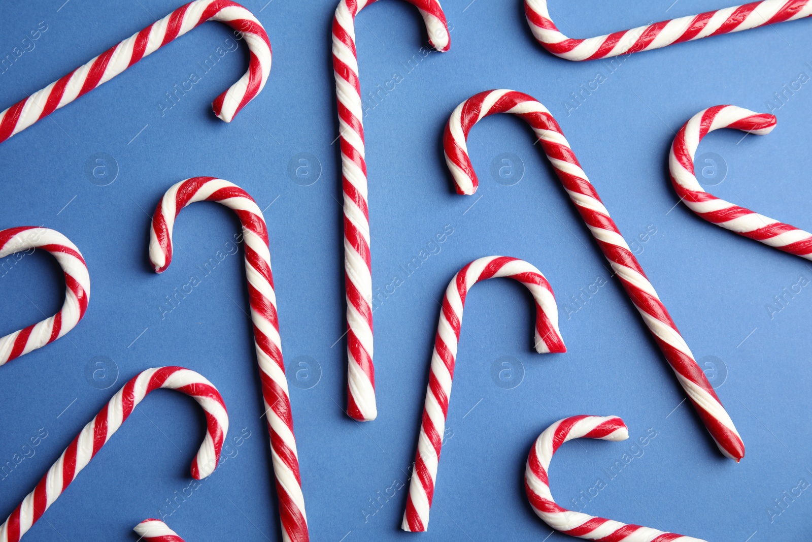 Photo of Candy canes on blue background, flat lay