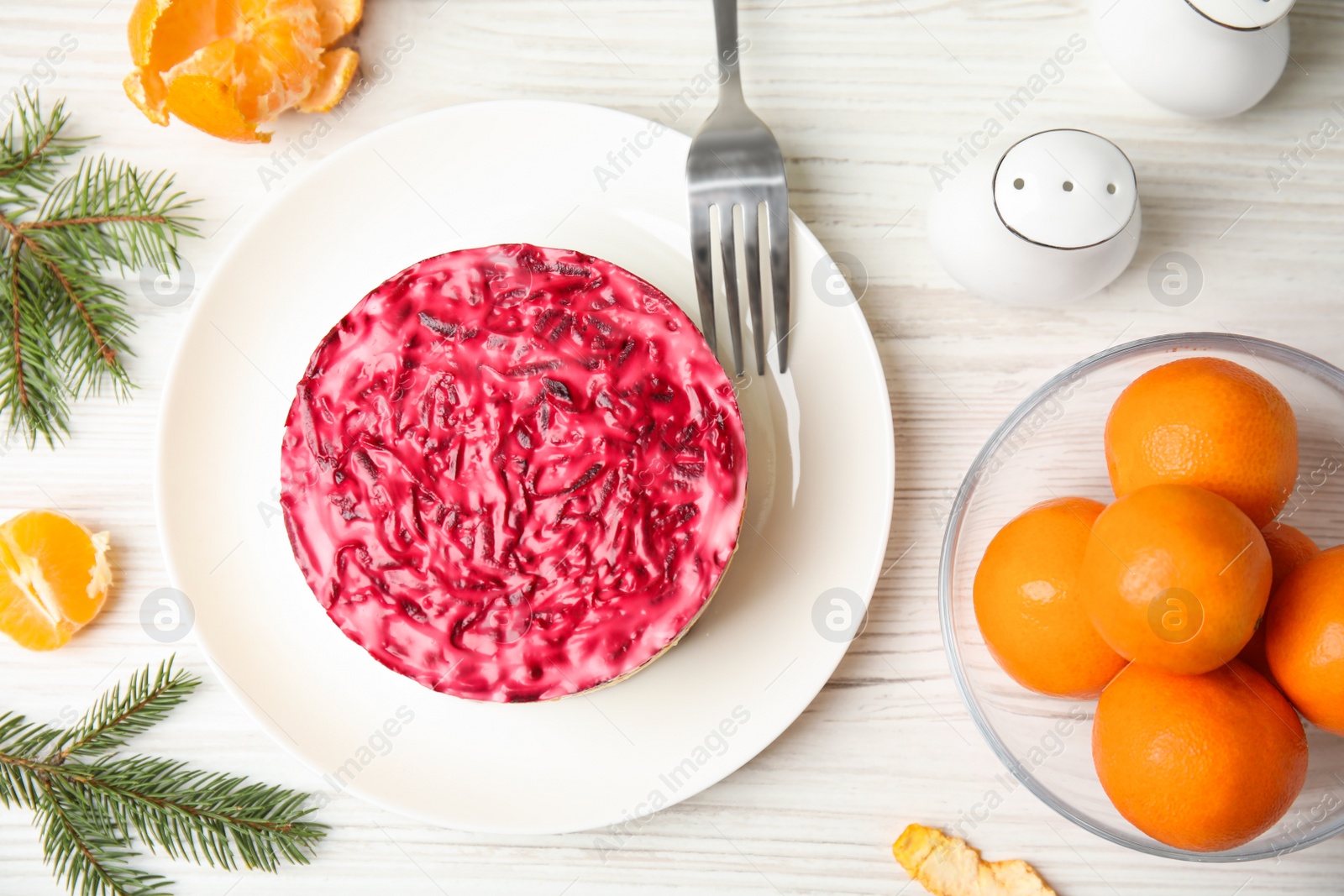 Photo of Flat lay composition with herring under fur coat, tangerines and fir branches on white wooden table. Traditional russian salad