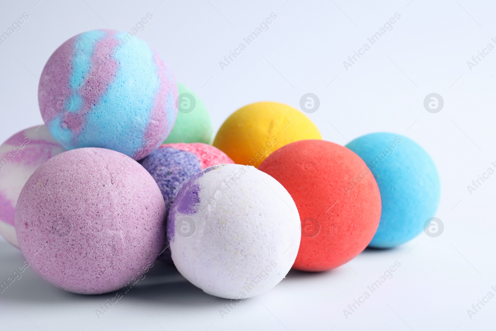 Photo of Pile of colorful bath bombs on white background, closeup