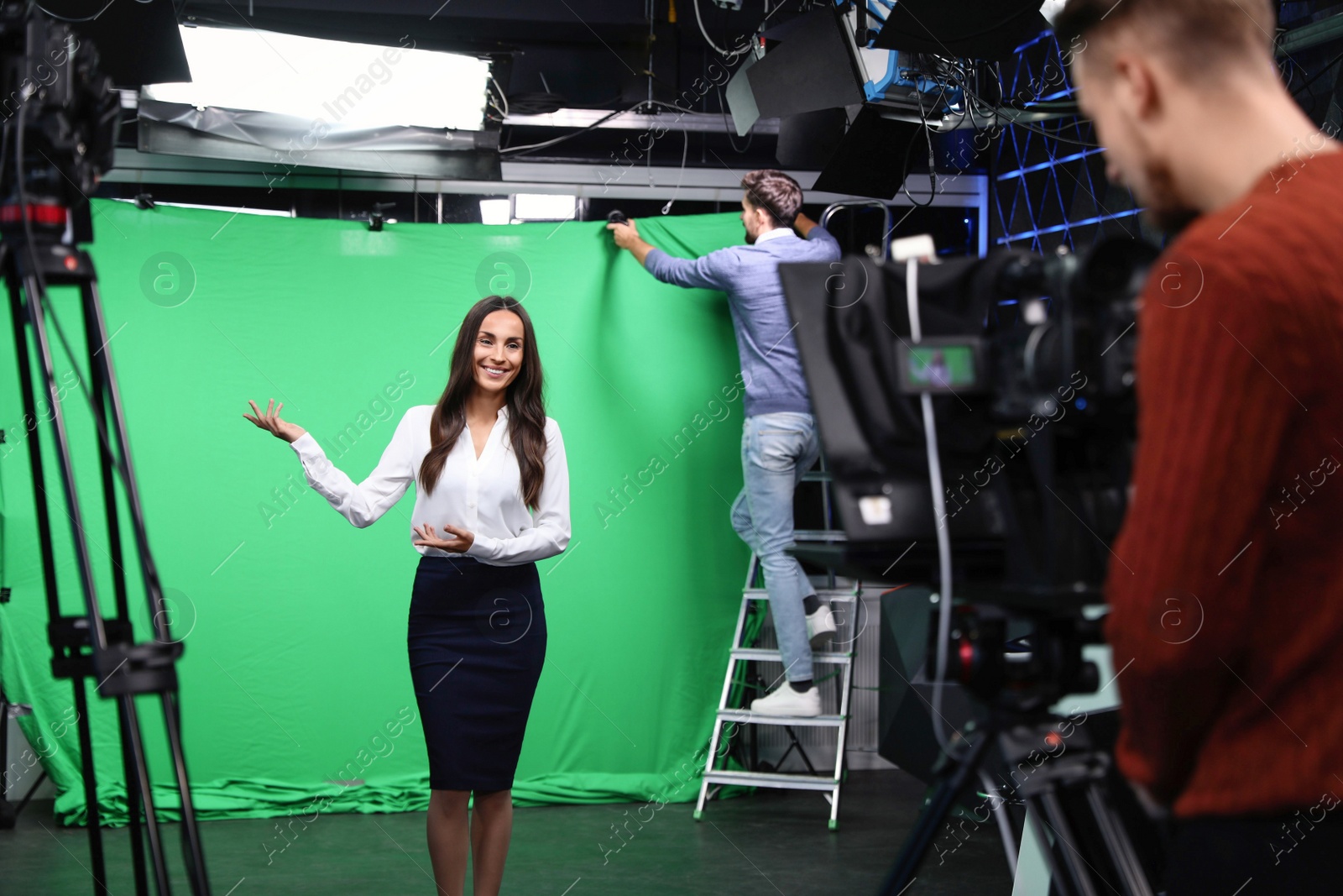 Photo of Presenter, technician and video camera operator working in studio. News broadcasting