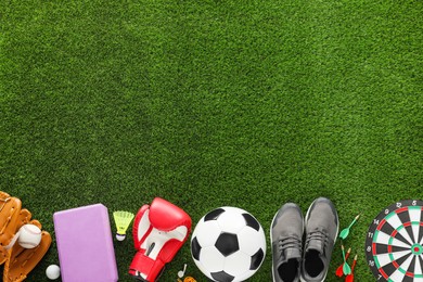 Photo of Different sport equipment and sneakers on green grass, flat lay. Space for text