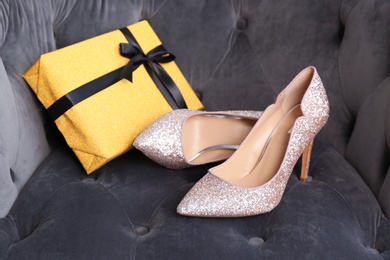 Elegant female shoes and gift box on armchair