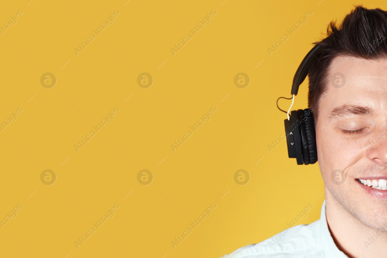 Photo of Man enjoying music in headphones on color background, closeup. Space for text