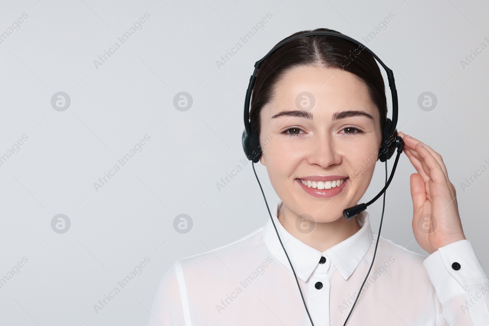 Photo of Hotline operator with modern headset on light grey background, space for text. Customer support