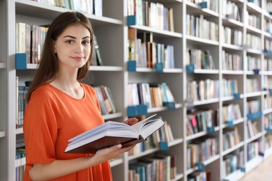 Young beautiful woman with book in library