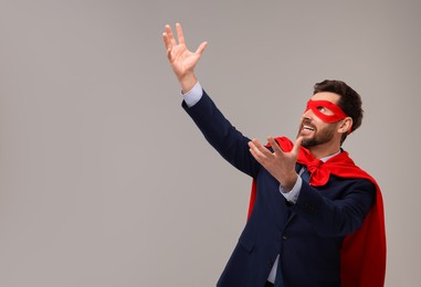 Photo of Businessman wearing red superhero cape and mask on beige background. Space for text