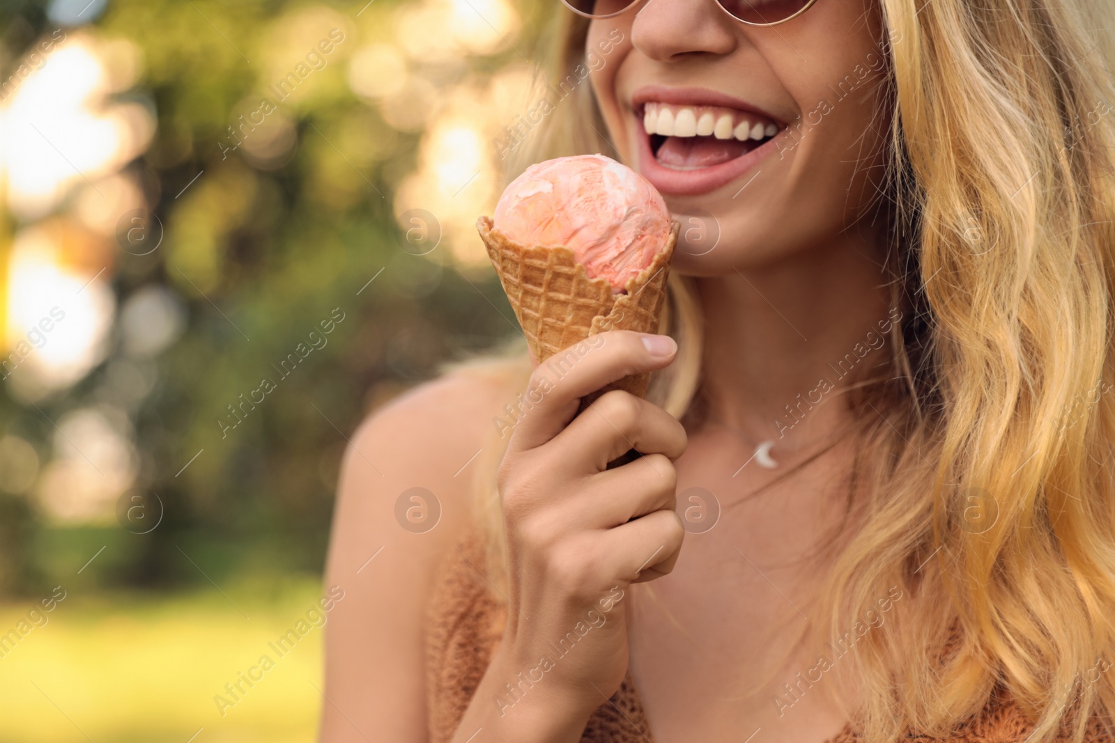 Photo of Young woman with delicious ice cream in waffle cone outdoors, closeup