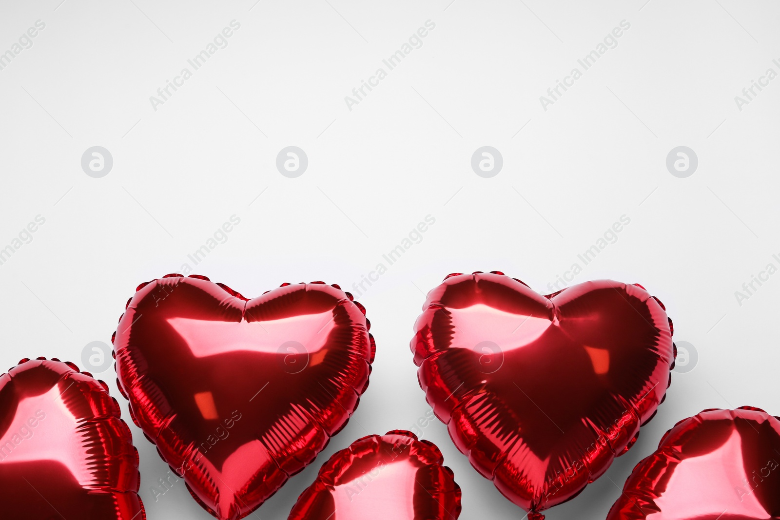 Photo of Red heart shaped balloons on white background, flat lay with space for text. Valentine's Day celebration