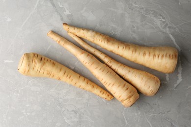Many fresh ripe parsnips on grey marble table, flat lay