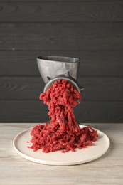 Photo of Metal meat grinder with beef mince on light wooden table