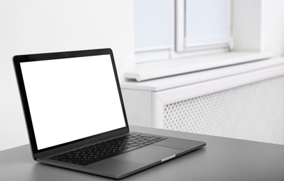 Modern laptop with blank screen on table indoors