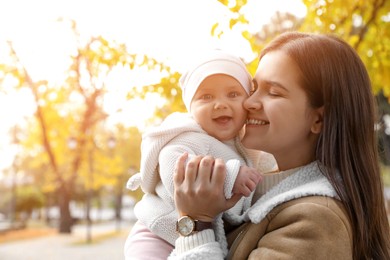 Photo of Happy mother with her baby daughter in park on autumn day, space for text