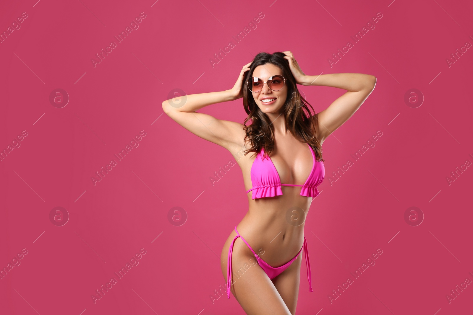 Photo of Beautiful woman in stylish bikini and sunglasses on crimson background