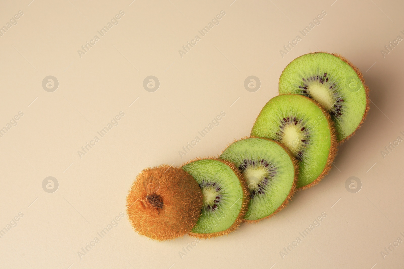 Photo of Sliced fresh kiwi on beige background, flat lay. Space for text