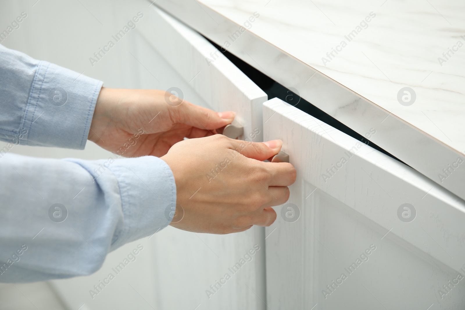 Photo of Woman opening cabinet doors at home, closeup