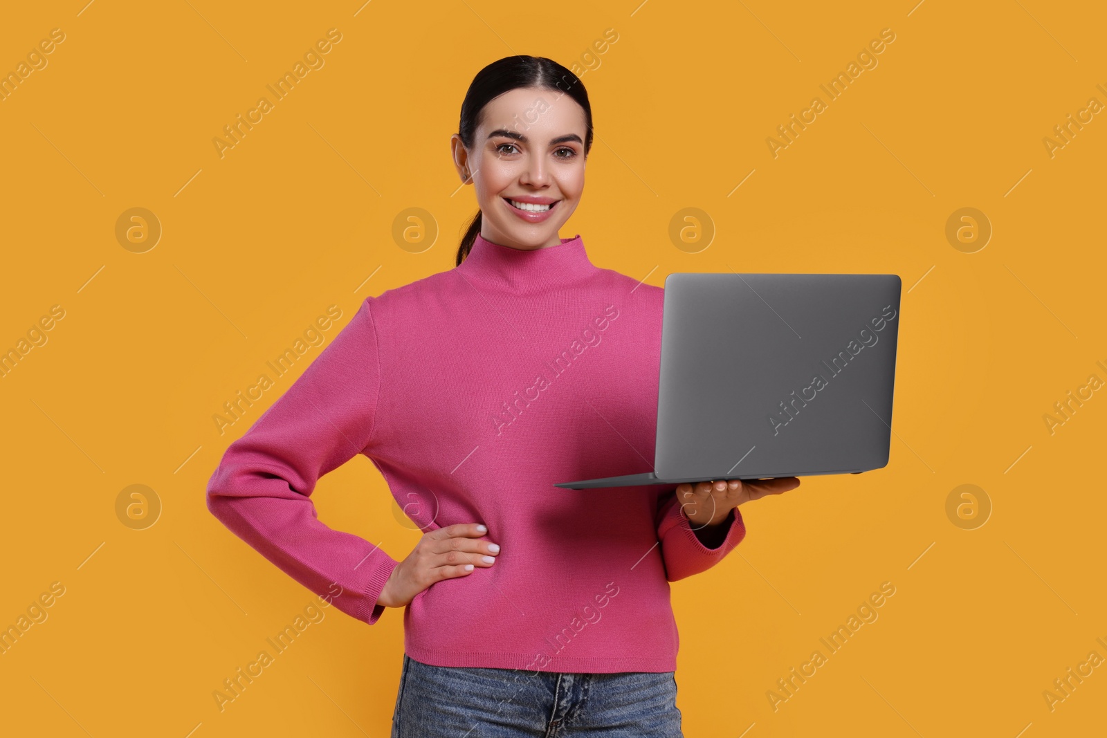 Photo of Happy woman with laptop on orange background