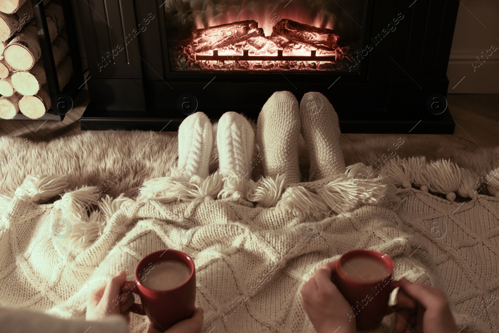 Photo of Couple in knitted socks near fireplace at home, closeup