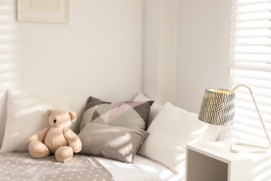 Photo of Teddy bear on bed in modern child room. Interior design