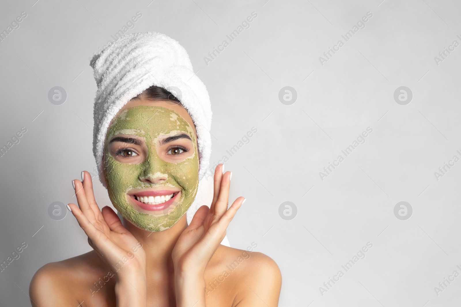 Photo of Young woman with clay mask on her face against light background, space for text. Skin care