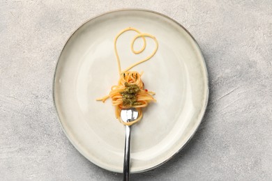 Photo of Heart made with spaghetti and fork on grey table, top view