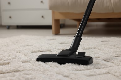 Hoovering carpet with vacuum cleaner indoors, closeup