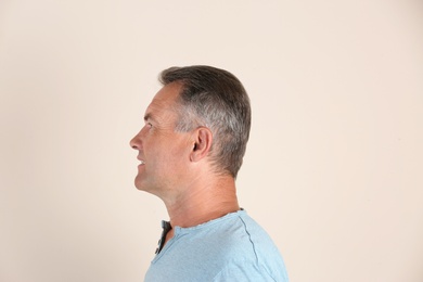 Mature man on light background. Hearing problem